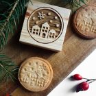 házak és hópelyhek mintájú keksz és fából készült kekszpecsét, vágódeszkán csipkebogyóval, fenyőággal